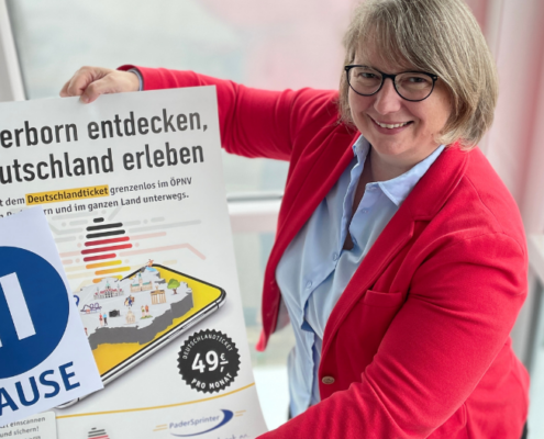 Eine Frau hält ein Plakat für die AboPause beim Deutschaldticket hoch