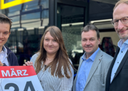 Vier Mitarbeiter des PaderSprinter stehen vor einem Bus und halten ein Plakat mit dem Motiv des Fahrplanswechsels hoch.