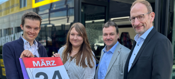 Vier Mitarbeiter des PaderSprinter stehen vor einem Bus und halten ein Plakat mit dem Motiv des Fahrplanswechsels hoch.