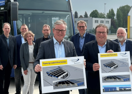 Es stehen 10 Personen vor einem Wasserstoffbus auf dem Betriebshof des PaderSprinter. NRW-Minister Oliver Krischer, Paderborns Bürgermeister Michael Dreier und PaderSprinter-Geschäftsführer Oliver Eikenberg halten Hartschaumplatten in die Kamera.