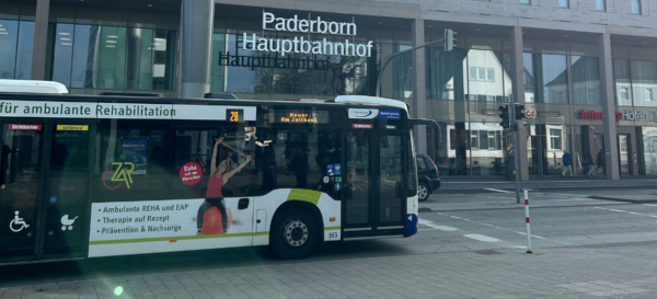 Ein Bus des PaderSprinters fährt vor dem Bahnhofsgebäude des Paderborner Hauptbahnhofs her