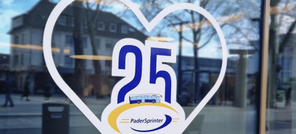 Die Grafik zeigt einen Aufkleber auf einer Glasscheibe. Der Aufkleber ist ein Herz mit dem Jubiläumslogo des PaderSprinter in der Mitte.