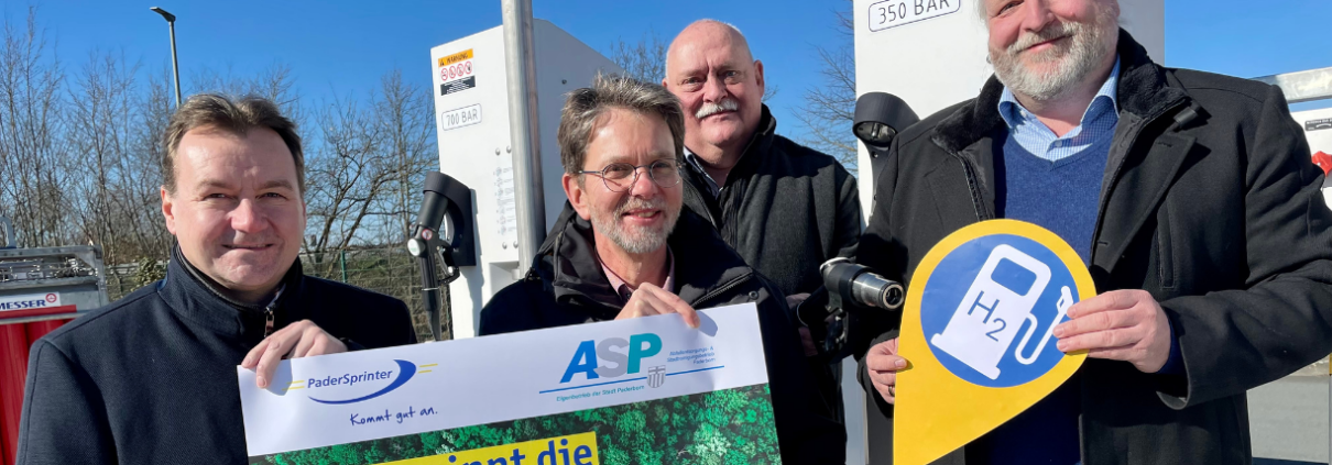 Vier Personen präsentieren die Wasserstofftankstelle des PaderSprinters