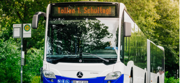 Ein Bus steht vor Bäumen mit dem Anzeigetext "Tollen 1. Schultag"