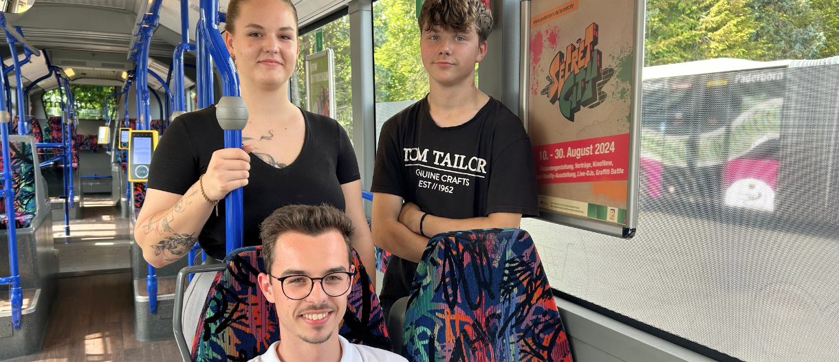 Drei Auszubildende stehen im Bus.