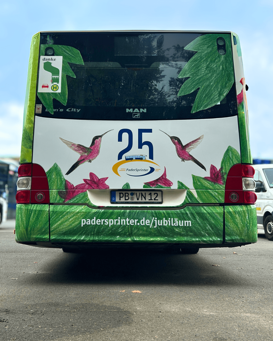 Heckansicht des PaderSprinter Jubiläumsbusses mit der Zahl 25, zwei Kolibris und dem PaderSprinter-Logo, darunter die Webseite padersprinter.de/jubiläum.