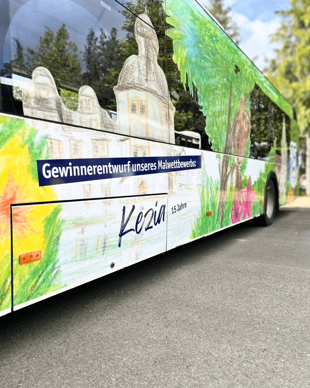 Nahaufnahme der Seitenbemalung des PaderSprinter Busses, die den Gewinnerentwurf eines Malwettbewerbs zeigt, mit dem Schriftzug "Kezia 15 Jahre".