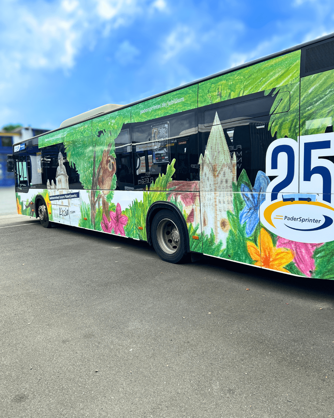 Seitenansicht des grün bemalten PaderSprinter Jubiläumsbusses mit stilisierten Bäumen, Blumen und Schloß Neuhaus mit der Kirche zu sehen, sowie der Zahl 25 und dem PaderSprinter-Logo.