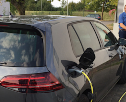 Bernhard Hengsbach und Philipp Bosseler betanken ein Elektroauto an einer der neuen Ladesäulen am Betriebshof