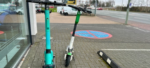 Zwei E-Tretroller auf einer gepflasterten Fläche an einer Straße