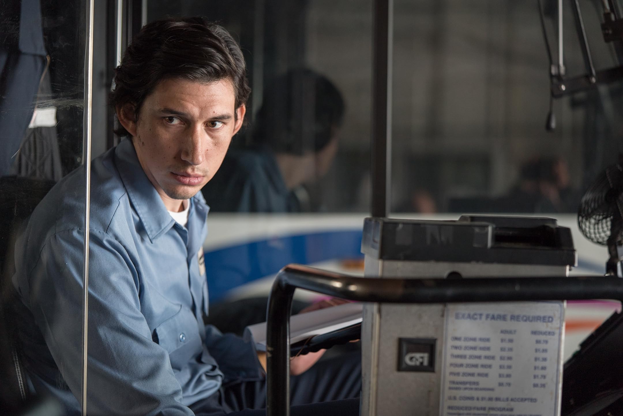 Das Bild zeigt eine Filmszene aus dem Film "Paterson". Der Hauptcharakter sitzt in einem Bus am Fahrerplatz.